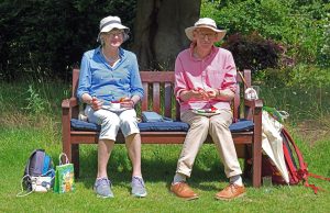 Two guests sitting on a bench enjoying afternooon tea