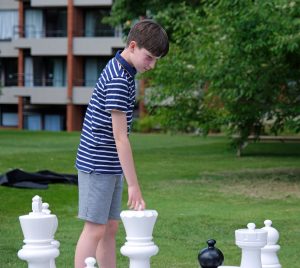 A boy playing giant chess.